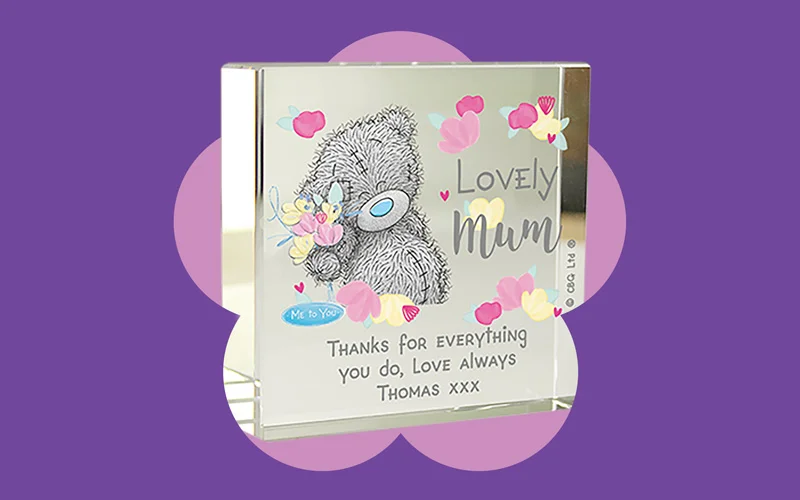 A glass block featuring a Tatty Teddy illustration with colourful hearts and the message ‘Lovely Mum,’ displayed on a purple background.