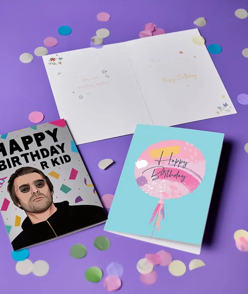 Selection of birthday cards displayed on a purple background with scattered confetti, including a balloon design and a novelty character card.