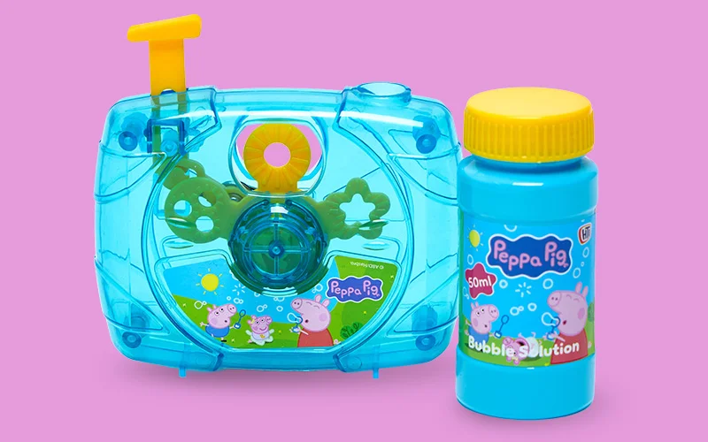 A blue Peppa Pig bubble‑making toy shaped like a camera, shown alongside a matching bottle of Peppa Pig bubble solution on a pink background.