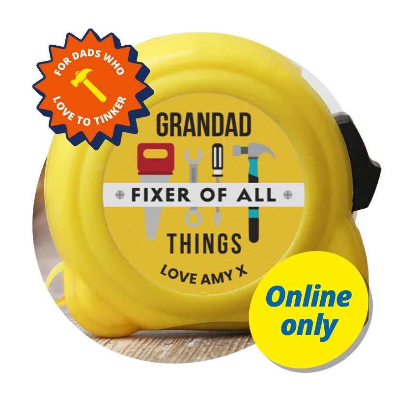 A yellow tape measure featuring a circular label printed with tools and the text ‘Grandad Fixer of All Things Love Amy x,’ displayed on a wooden surface against a bright orange background with a ‘For dads who love to tinker’ badge and a yellow ‘Online only’ label. A yellow tape measure featuring a circular label printed with tools and the text ‘Grandad Fixer of All Things Love Amy x,’ displayed on a wooden surface against a bright orange background with a ‘For dads who love to tinker’ badge and a yellow ‘Online only’ label.