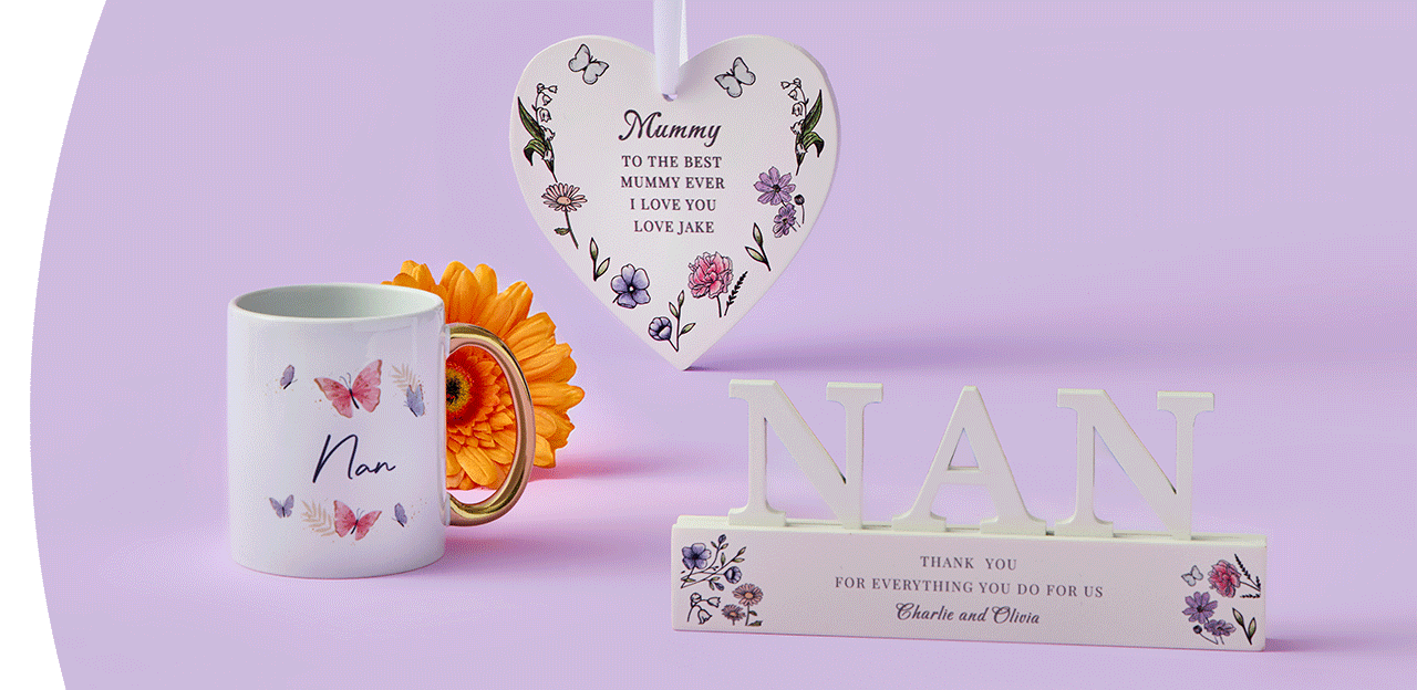 Butterfly‑themed Nan mug, a pink and cream Mum’s coffee mug, a floral heart plaque with a loving message, and a decorative NAN sign arranged together on a pastel purple background.
