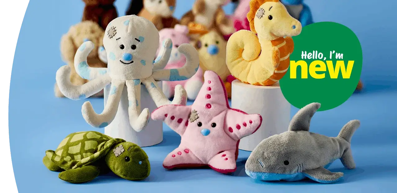 A group of soft plush sea animal toys arranged on a blue background, including an octopus, starfish, turtle, seahorse, and shark, with a green badge reading hello, I’m new.
