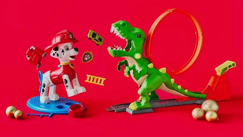 Toy Dalmatian firefighter and green dinosaur on a red background with a loop track, flying toy cars, firefighting accessories, and gold Christmas ornaments. Toy Dalmatian firefighter and green dinosaur on a red background with a loop track, flying toy cars, firefighting accessories, and gold Christmas ornaments.