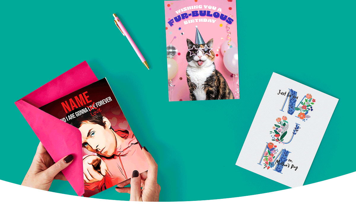 A set of colourful greeting cards arranged on a teal background, including one being placed into a bright pink envelope, a cat‑themed birthday card, and a floral card beside a matching pen.