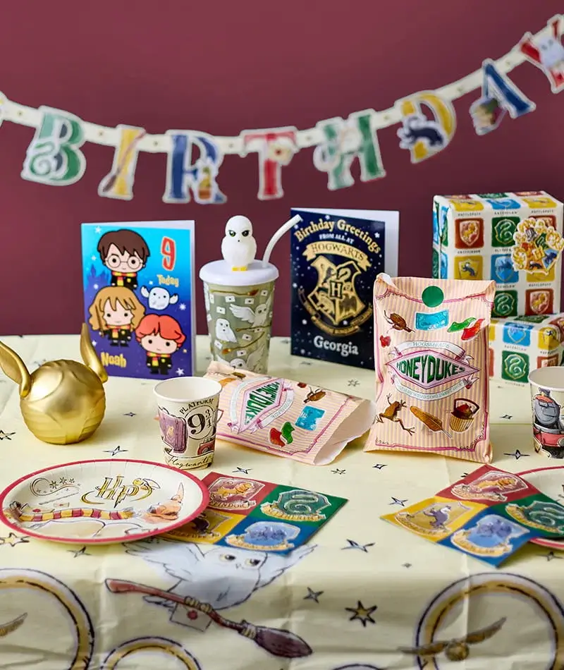 Harry Potter themed birthday party setup featuring party tableware, birthday cards, Hogwarts-inspired decorations, sweet bags and a colourful birthday banner.