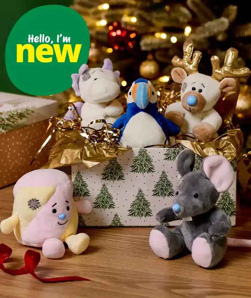 Selection of festive Beanie Bellies soft toys, including a penguin, reindeer, mouse and unicorn, displayed in a Christmas gift box in front of a decorated Christmas tree.