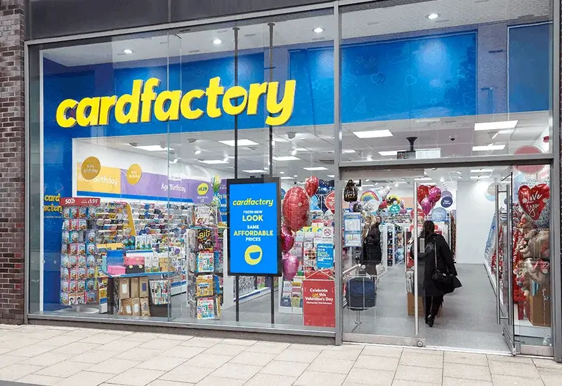 Card Factory store front with greeting card displays, balloon arrangements, gift ranges, and bright blue branding visible through the glass entrance.