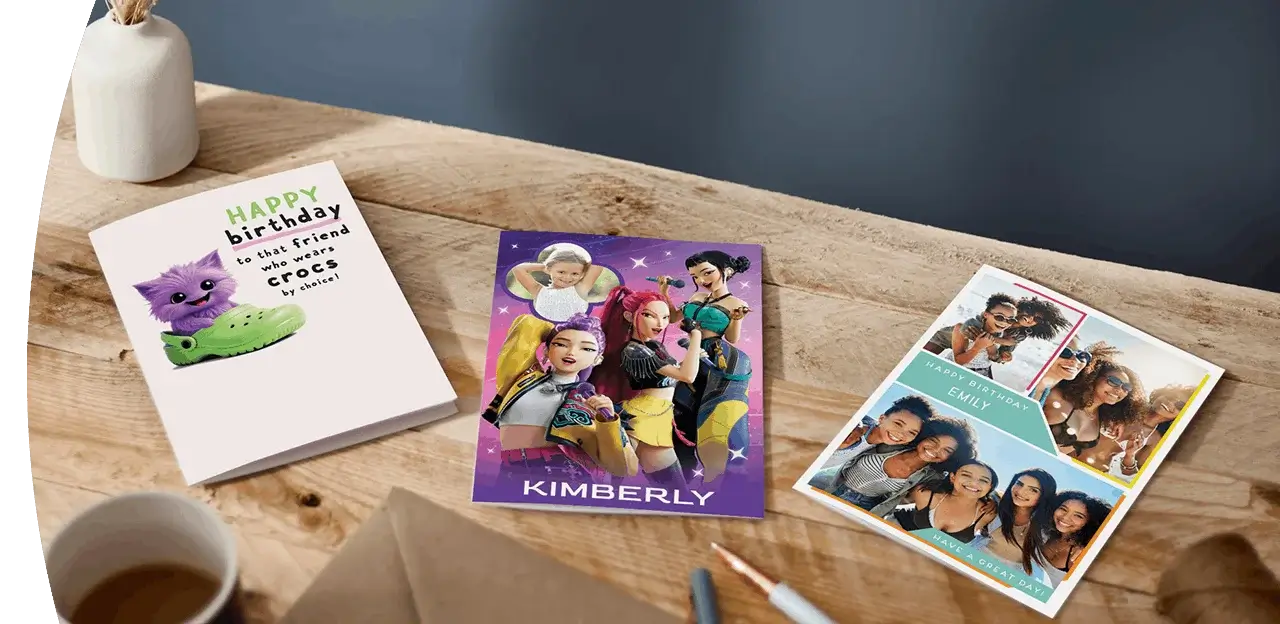 Selection of greeting cards including personalised photo cards, a character-themed birthday card, and a humorous birthday card displayed on a wooden table. Selection of greeting cards including personalised photo cards, a character-themed birthday card, and a humorous birthday card displayed on a wooden table.
