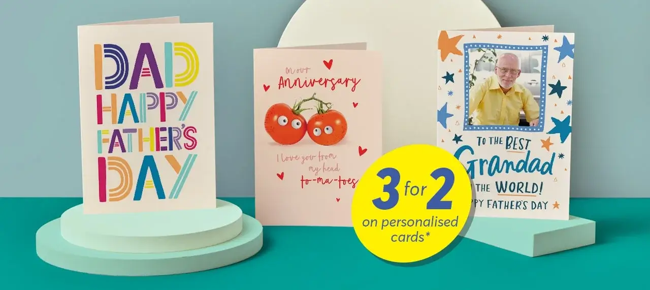 'The image shows three greeting cards displayed on a purple background with a circular platform. The first card on the left is blue with the text 'Happy Birthday to You!' in colorful letters. The middle card is cream-colored with two tomatoes and the text 'Our 1st Anniversary' and 'I love you from my head to-ma-toes'. The third card on the right has multiple photos of people, the number '17', and the text 'Happy Birthday Elizabeth'. A yellow circular sign in front of the cards reads '3 for 2 on personalised cards*'