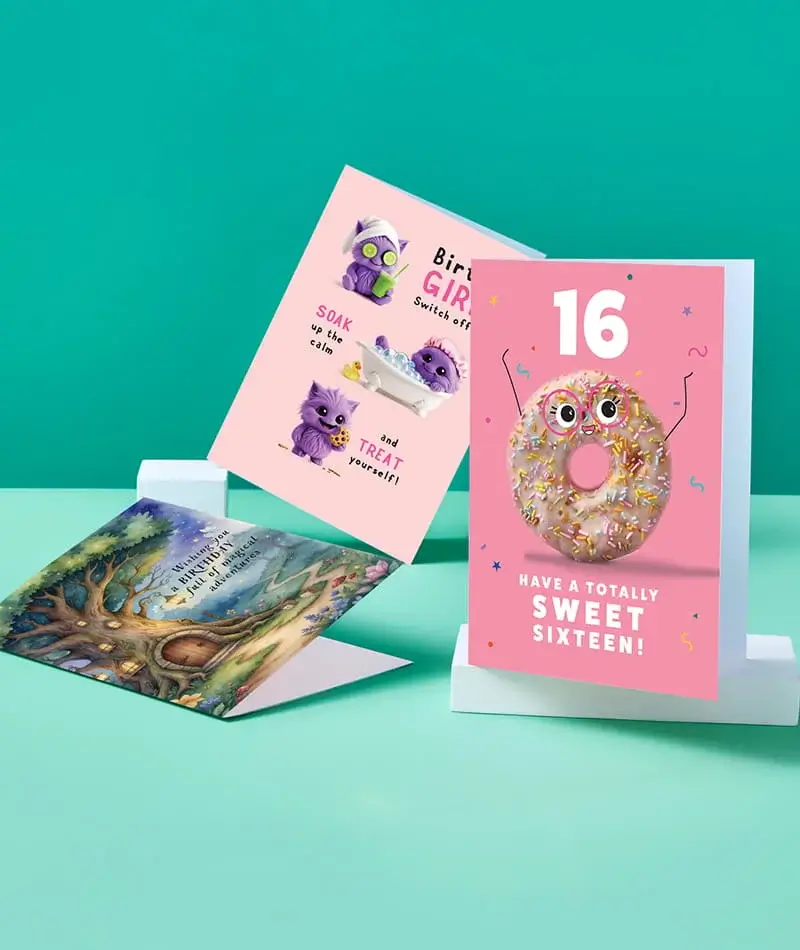 Selection of birthday cards featuring humour, fantasy, and football-themed designs displayed on stands against a teal background Selection of birthday cards featuring humour, fantasy, and football-themed designs displayed on stands against a teal background