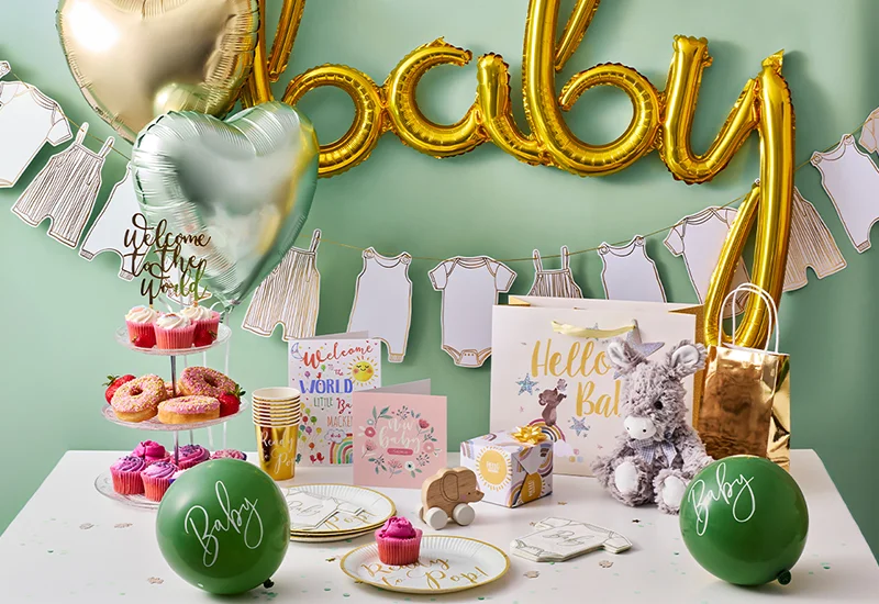 A neutral-toned baby shower display featuring a sage green, cream and mocha balloon garland, ‘Baby’ backdrop, personalised baby shower sign and stacked BABY blocks.
