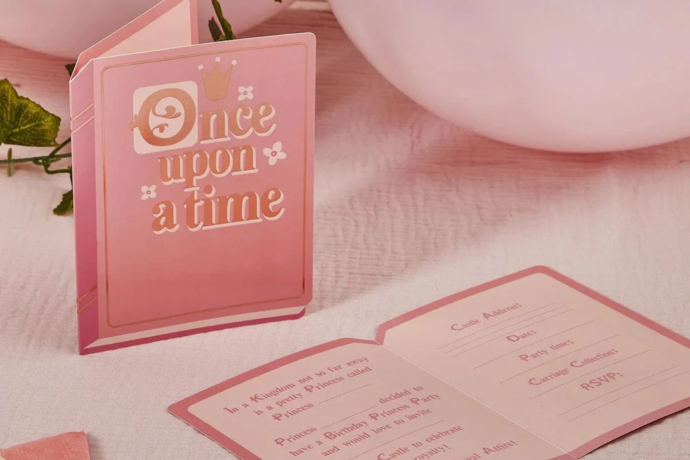 A princess-themed party invitation styled as a pink storybook with gold foil text reading ‘Once upon a time,’ displayed beside an open invitation card featuring a fairytale-style party message and spaces to complete event details such as date, time and RSVP. A princess-themed party invitation styled as a pink storybook with gold foil text reading ‘Once upon a time,’ displayed beside an open invitation card featuring a fairytale-style party message and spaces to complete event details such as date, time and RSVP.