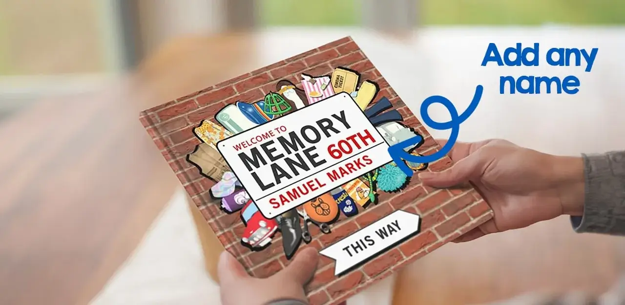 A person holding a book with a brick wall cover design. The book title reads 'Welcome to Memory Lane 60th Samuel Marks' with illustrated nostalgic items like toys, shoes, and clothing. An arrow at the bottom points right with the text 'This Way'