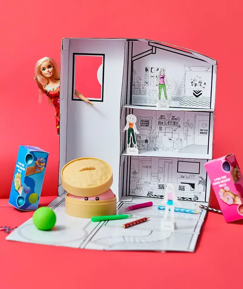 Colour-in Barbie doll house playset with colouring pens, pop-out figures, and interactive accessories on a bright pink background. Colour-in Barbie doll house playset with colouring pens, pop-out figures, and interactive accessories on a bright pink background.