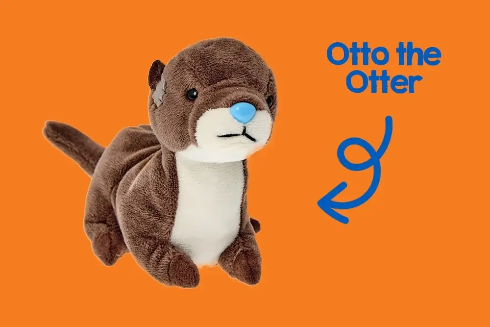 A plush toy otter with a brown body, white belly, and blue nose is sitting against a pink background. A plush toy otter with a brown body, white belly, and blue nose is sitting against a pink background.