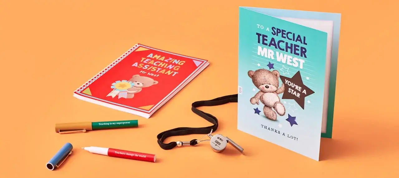 A thank you card and a notebook for teachers are displayed with pens and a lanyard. The red notebook reads 'AMAZING TEACHING ASSISTANT Mr West' with a bear holding flowers. The blue card says 'TO A SPECIAL TEACHER MR WEST YOU'RE A STAR THANKS A LOT!' with a bear holding a star. Three pens—green, blue, and red—are included, along with a black lanyard with keys.