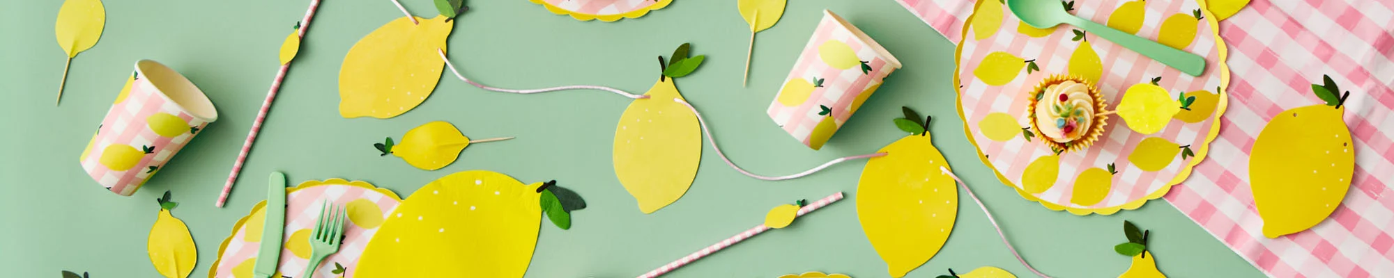 A lemon-themed party table setting arranged on a mint green background, featuring gingham pink-and-white plates decorated with lemon illustrations, matching paper cups, straws, napkins and cutlery. Lemon-shaped place settings, garlands and cupcake toppers are scattered throughout the display, alongside cupcakes and coordinating party decorations in yellow, pink and green. A lemon-themed party table setting arranged on a mint green background, featuring gingham pink-and-white plates decorated with lemon illustrations, matching paper cups, straws, napkins and cutlery. Lemon-shaped place settings, garlands and cupcake toppers are scattered throughout the display, alongside cupcakes and coordinating party decorations in yellow, pink and green.