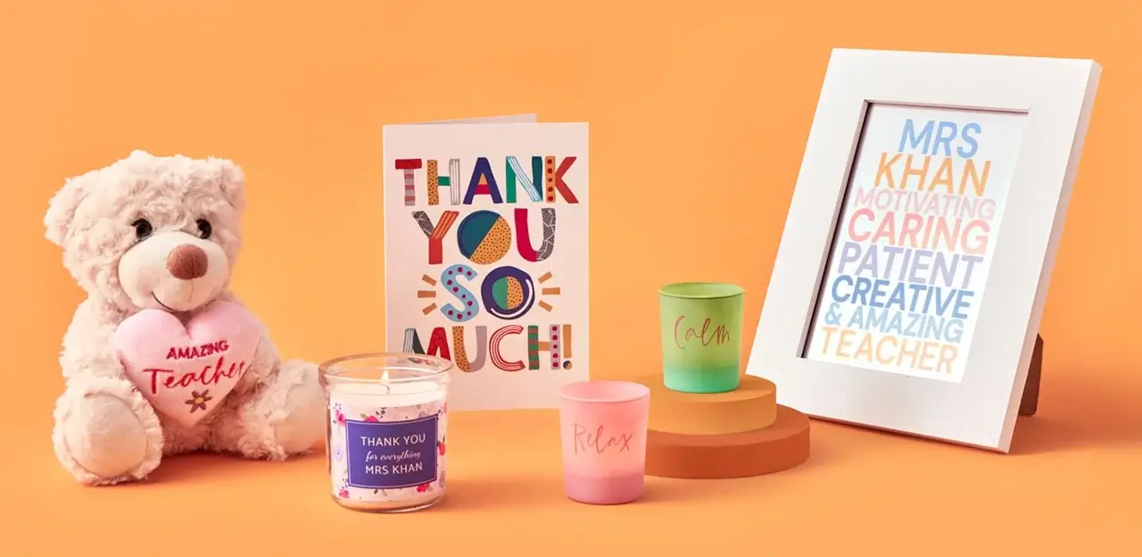 'A collection of teacher appreciation gifts including a teddy bear holding a heart with the text 'Amazing Teacher', a colorful thank you card, a candle with the text 'Thank you for an amazing Mrs. Khan', two small candles labeled 'Relax' and 'Calm', and a framed print with words describing Mrs. Khan such as motivating, caring, patient, creative, and amazing.'