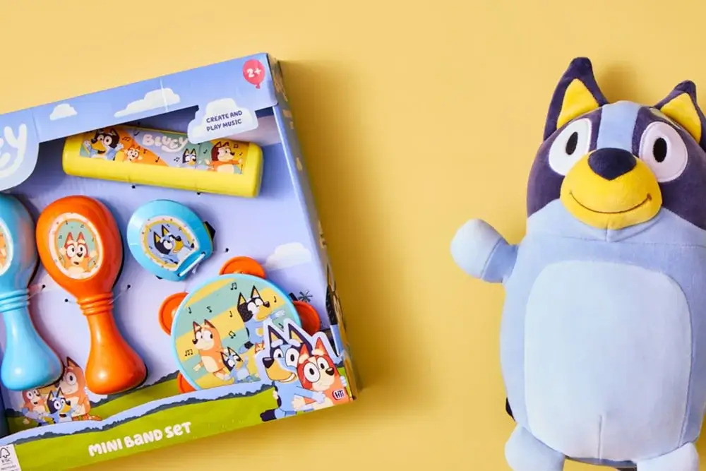 Bluey-themed mini band set with maracas, tambourine, and harmonica, alongside a Bluey plush toy on a yellow background.