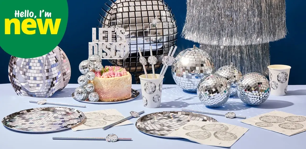 'The image shows a disco-themed party setup with various disco balls, a cake, and party supplies. There are large and small disco balls on the table and in the background. The cake is decorated with a 'LET'S DISCO' topper. Plates, cups, napkins, and straws all feature disco ball designs. A green circle in the top left corner has text that reads 'Hello, I'm new'
