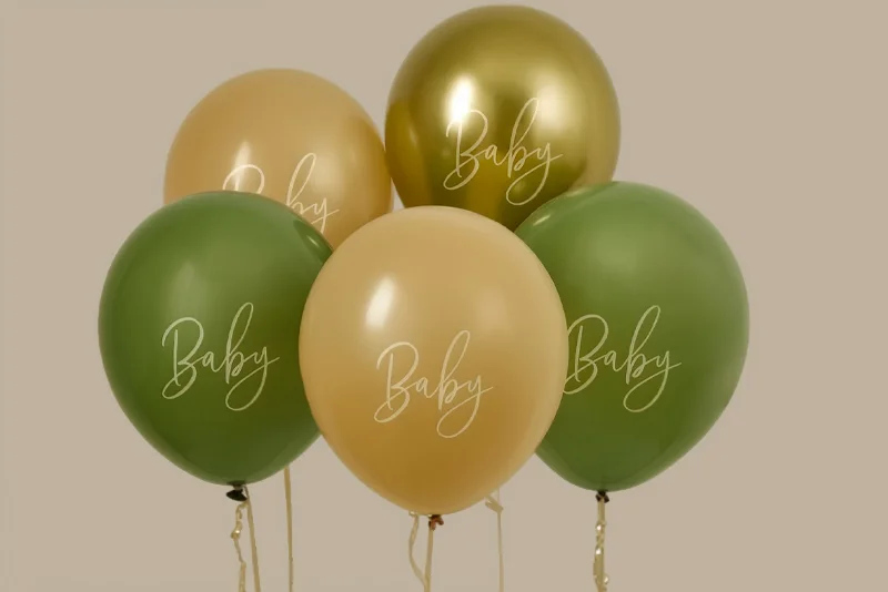 A cluster of five baby shower balloons in sage green, cream and metallic gold, each printed with the word ‘Baby’ in elegant script lettering. The balloons are grouped together against a neutral beige background, creating a stylish baby shower decoration.