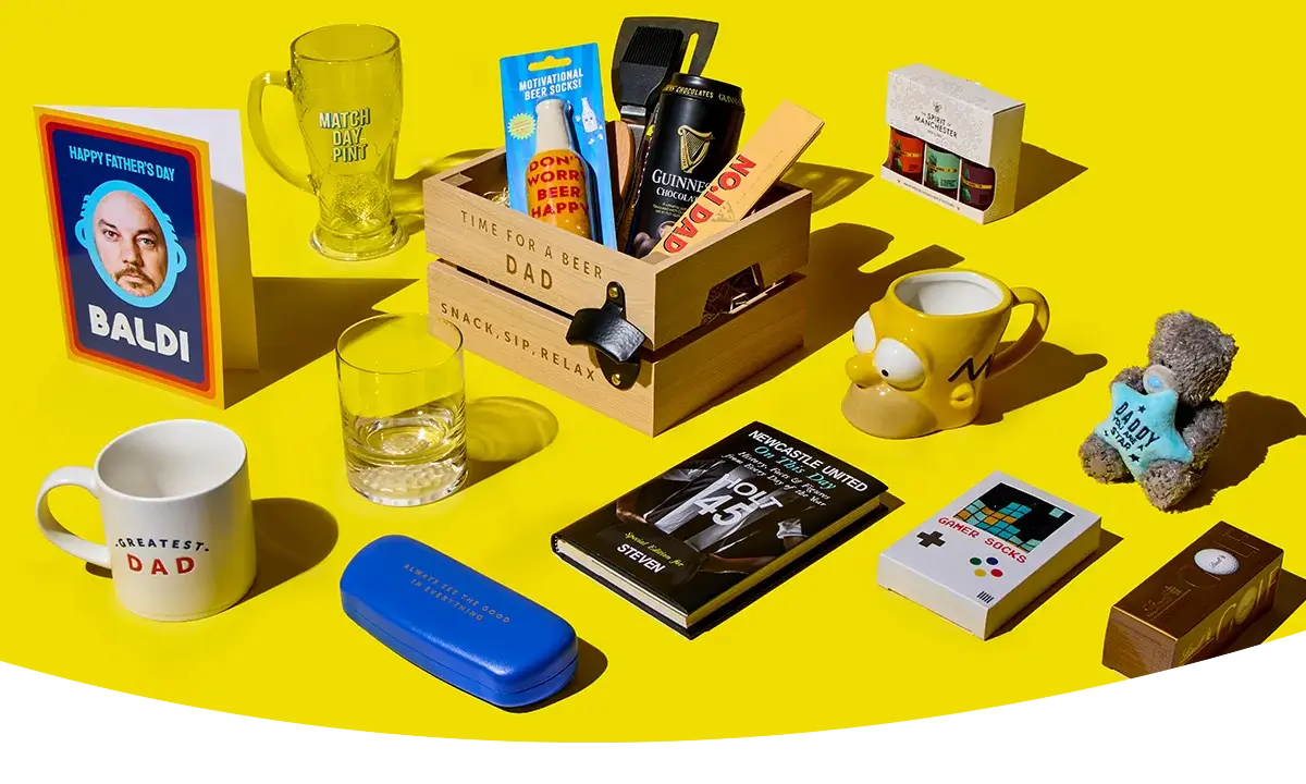 A Father’s Day gift display with a wooden crate filled with beer and snacks, surrounded by mugs, a glass, novelty socks, a book, cards and small gifts on a bright yellow background.
A Father’s Day gift display with a wooden crate filled with beer and snacks, surrounded by mugs, a glass, novelty socks, a book, cards and small gifts on a bright yellow background.