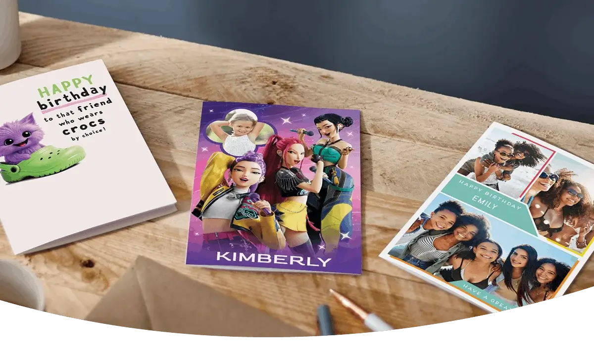 Selection of greeting cards including personalised photo cards, a character-themed birthday card, and a humorous birthday card displayed on a wooden table. Selection of greeting cards including personalised photo cards, a character-themed birthday card, and a humorous birthday card displayed on a wooden table.