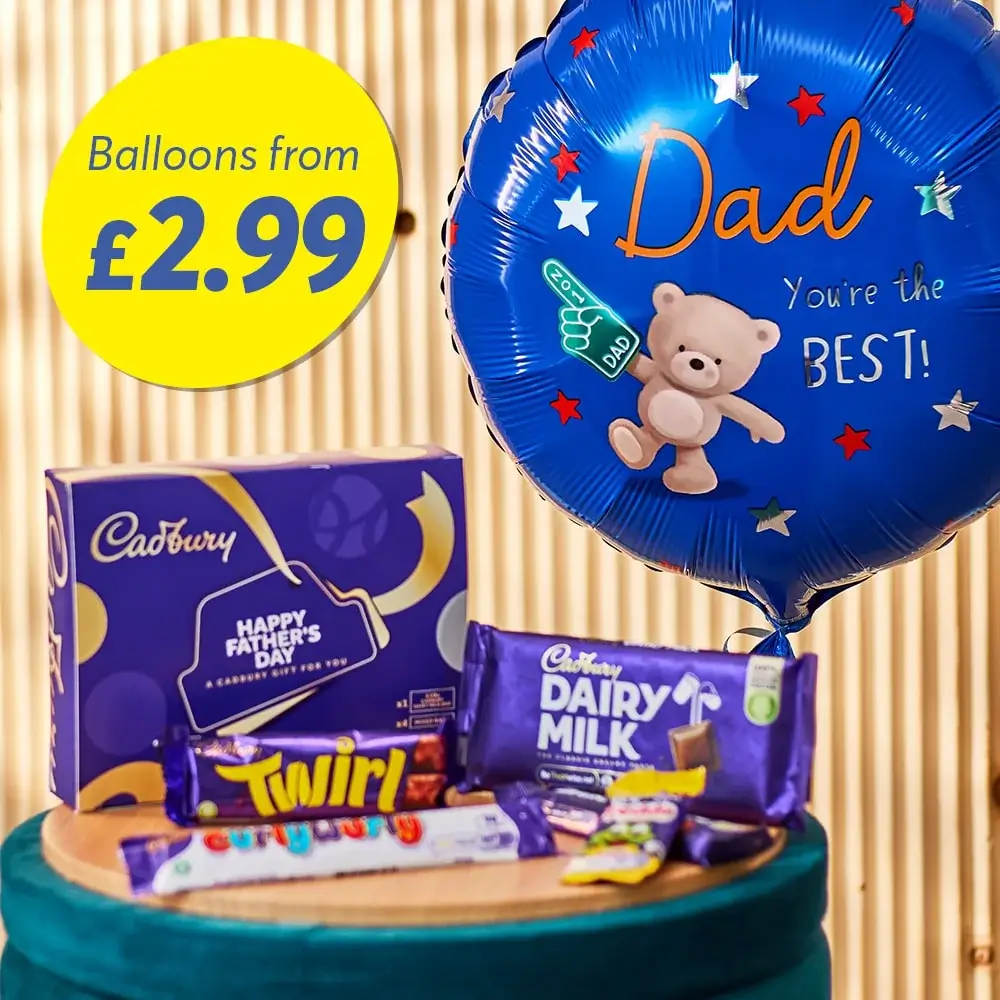 The image shows a blue balloon with the text 'Dad You're the BEST!' and a teddy bear holding a trophy. Next to it is a Cadbury gift box labeled 'Happy Father's Day' and several Cadbury chocolate bars, including Dairy Milk and Twirl. A yellow circle in the top left corner reads 'Balloons from £2.99'.