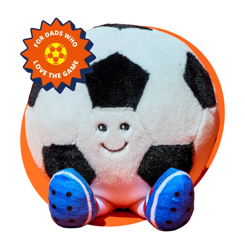 A soft plush toy designed like a black and white football with a smiling face and blue feet, displayed against a bright orange background, with a badge reading ‘For dads who love the game’ in the corner. A soft plush toy designed like a black and white football with a smiling face and blue feet, displayed against a bright orange background, with a badge reading ‘For dads who love the game’ in the corner.