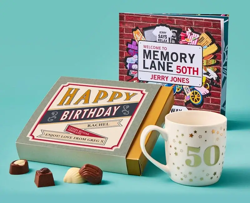 A collection of 50th birthday-themed items on a teal background, including a wine glass, a mug, a book, a gift box labeled 'Happy Birthday Rachel', and chocolates.