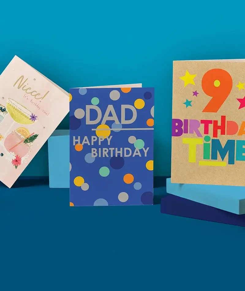 Three birthday cards are displayed against a blue background. The left card is pink with cocktail illustrations and the text 'Nice! It's birthday time!'. The middle card is blue with polka dots and the text 'DAD HAPPY BIRTHDAY'. The right card is brown with a large orange number 9 and the text 'BIRTHDAY TIME' Three birthday cards are displayed against a blue background. The left card is pink with cocktail illustrations and the text 'Nice! It's birthday time!'. The middle card is blue with polka dots and the text 'DAD HAPPY BIRTHDAY'. The right card is brown with a large orange number 9 and the text 'BIRTHDAY TIME'