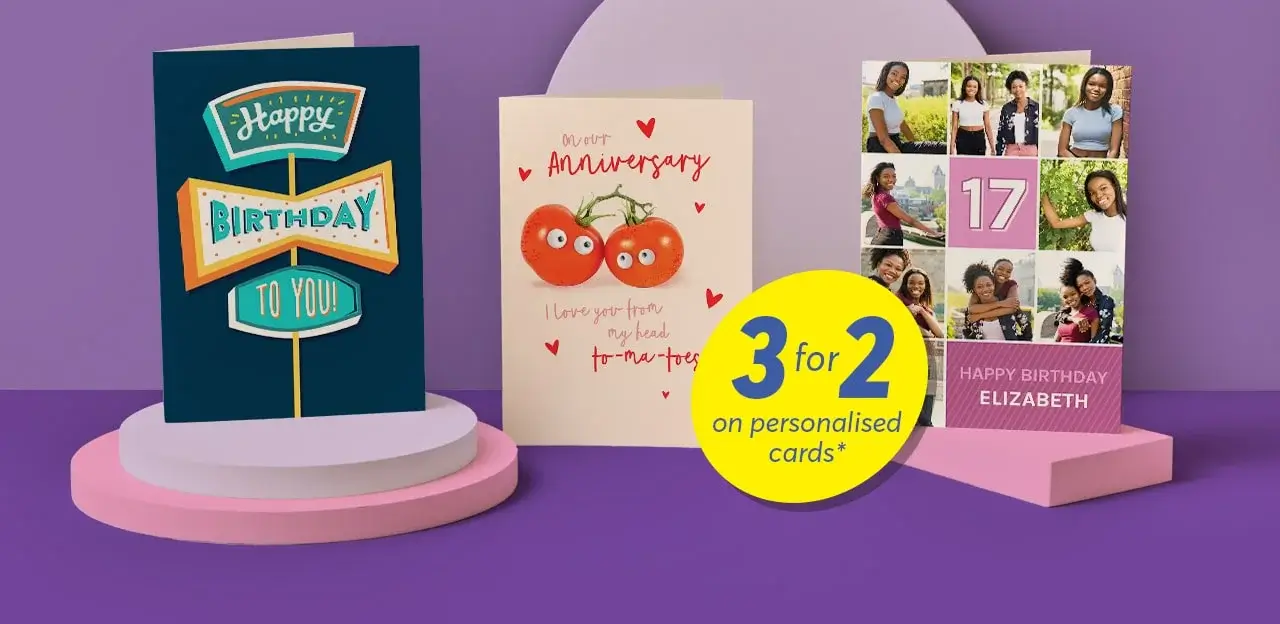'The image shows three greeting cards displayed on a purple background with a circular platform. The first card on the left is blue with the text 'Happy Birthday to You!' in colorful letters. The middle card is cream-colored with two tomatoes and the text 'Our 1st Anniversary' and 'I love you from my head to-ma-toes'. The third card on the right has multiple photos of people, the number '17', and the text 'Happy Birthday Elizabeth'. A yellow circular sign in front of the cards reads '3 for 2 on personalised cards*'