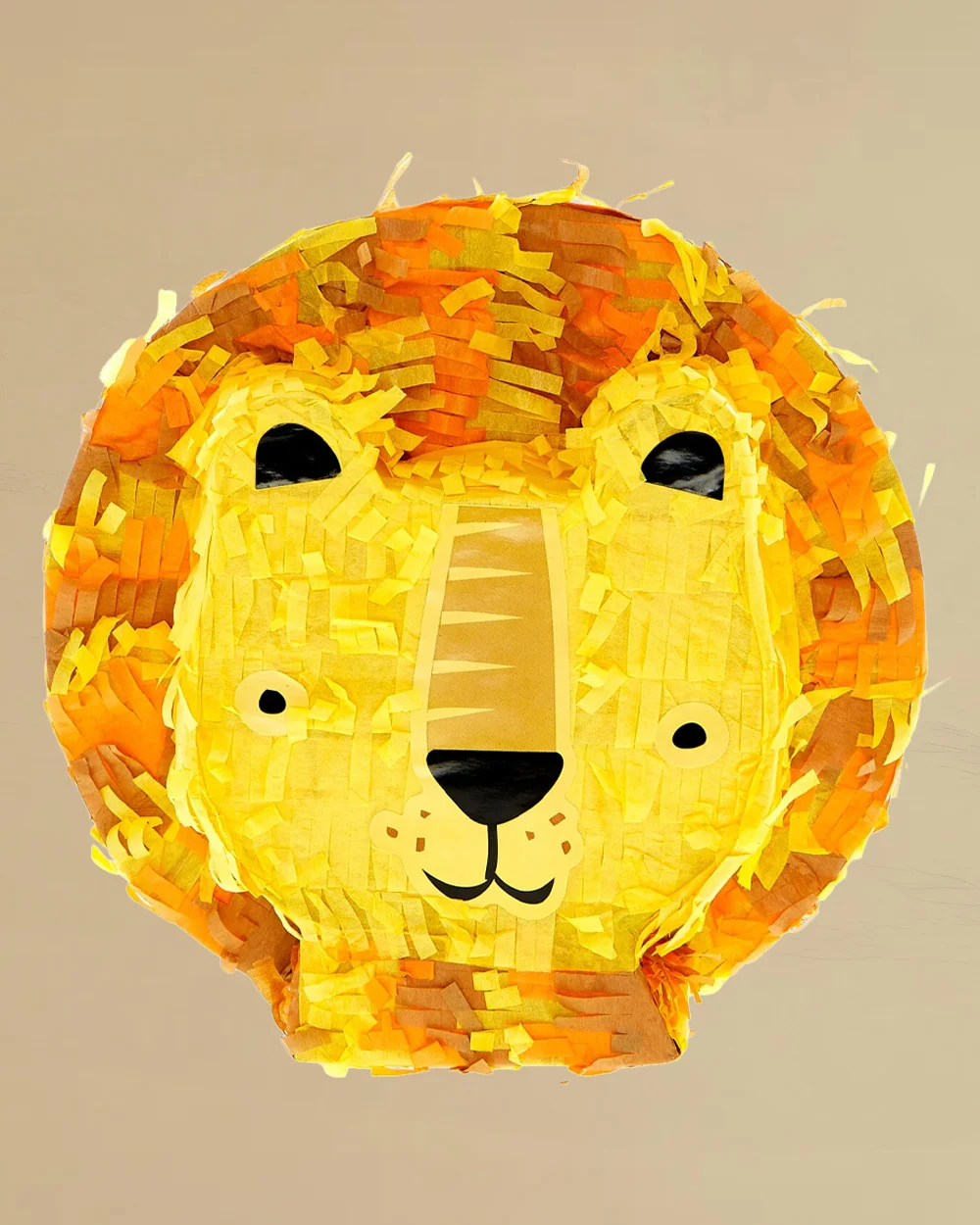A lion-shaped piñata covered in layered yellow and orange tissue paper fringe, featuring printed facial details and a stylised mane. The safari-themed party game decoration is displayed against a neutral beige background and is designed to be filled with sweets and treats for children's celebrations.