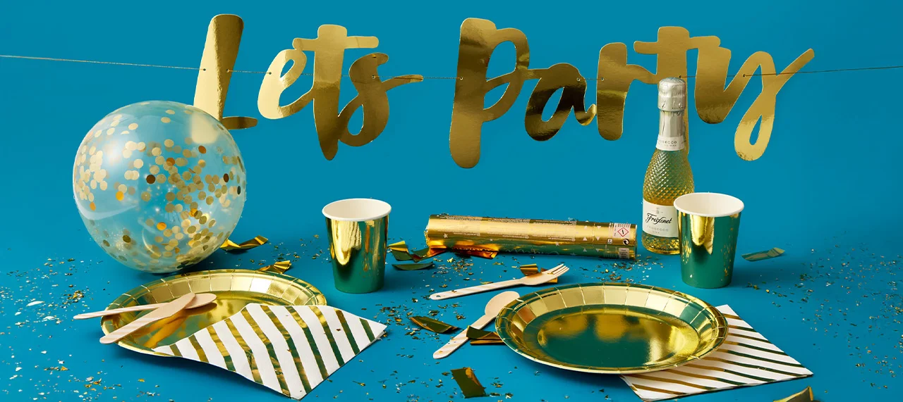 The image shows a flat lay of bridal shower or bachelorette party items on a pink background. There are two plates with the text 