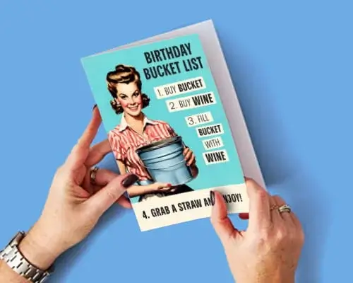 Humorous birthday card featuring a retro illustration, birthday bucket list joke, and wine-themed design held against a blue background.
