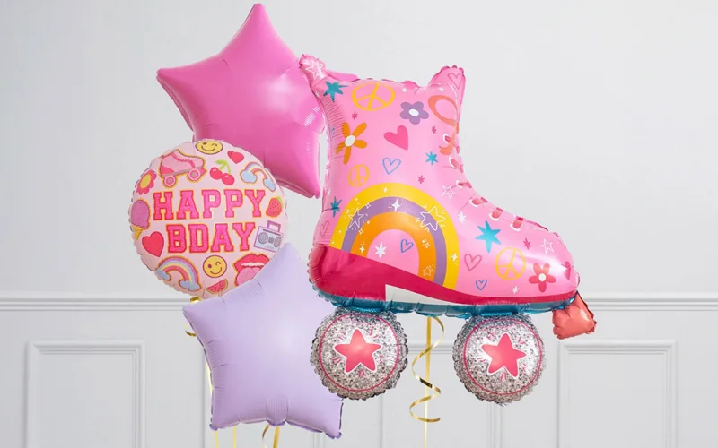A birthday balloon bouquet featuring a large pink roller skate foil balloon decorated with rainbow and flower designs, accompanied by pink and lilac star-shaped balloons and a round ‘Happy Bday’ balloon, displayed against a white background.