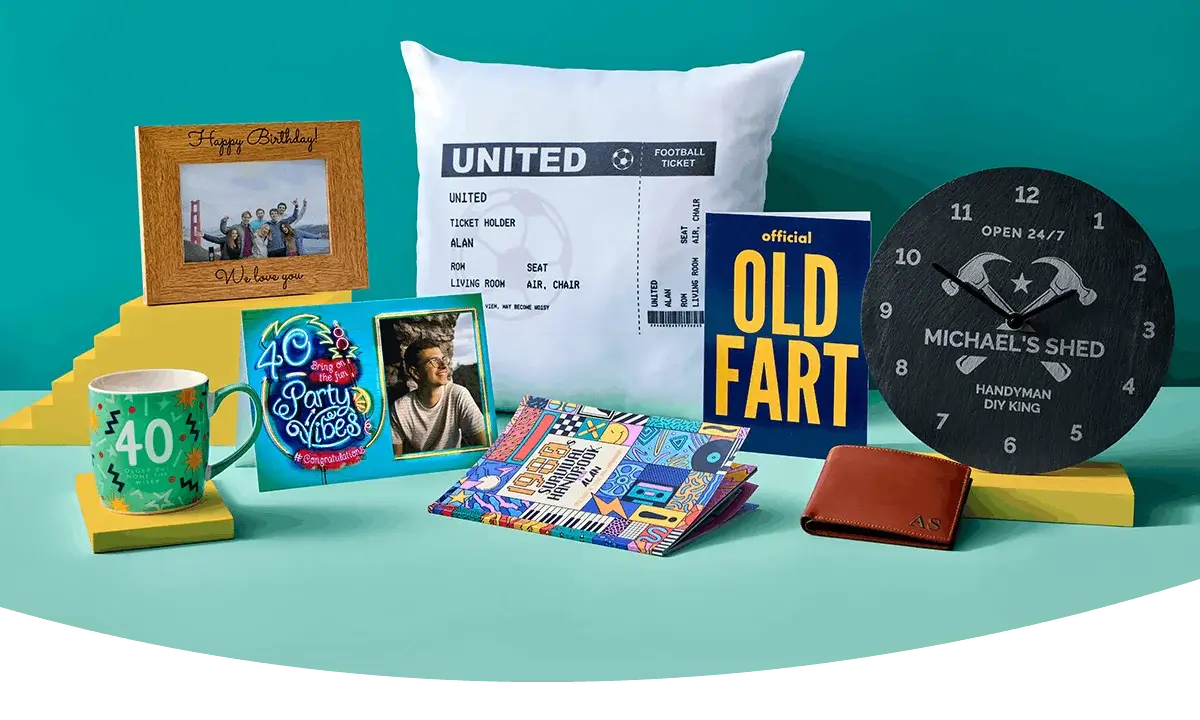 A display of personalised photo gifts on a peach background, including a photo frame, greeting cards, a birthday gift bag, a photo mug, and wrapped photo prints.