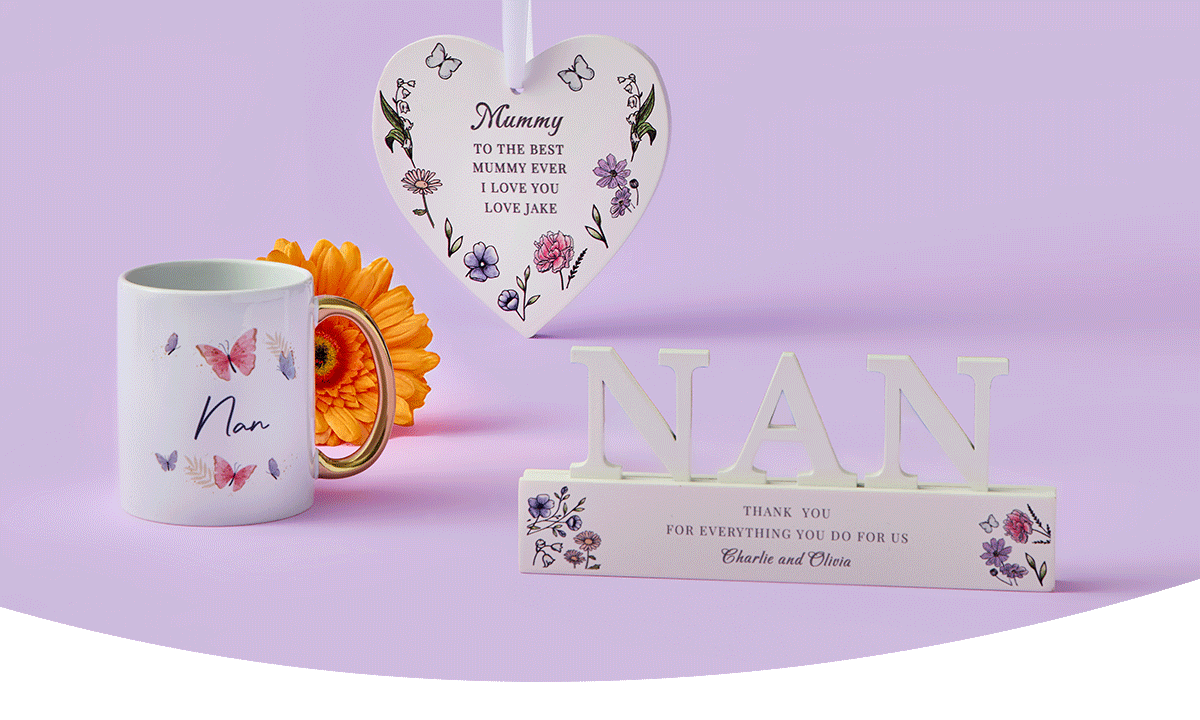 Butterfly‑themed Nan mug, a pink and cream Mum’s coffee mug, a floral heart plaque with a loving message, and a decorative NAN sign arranged together on a pastel purple background.