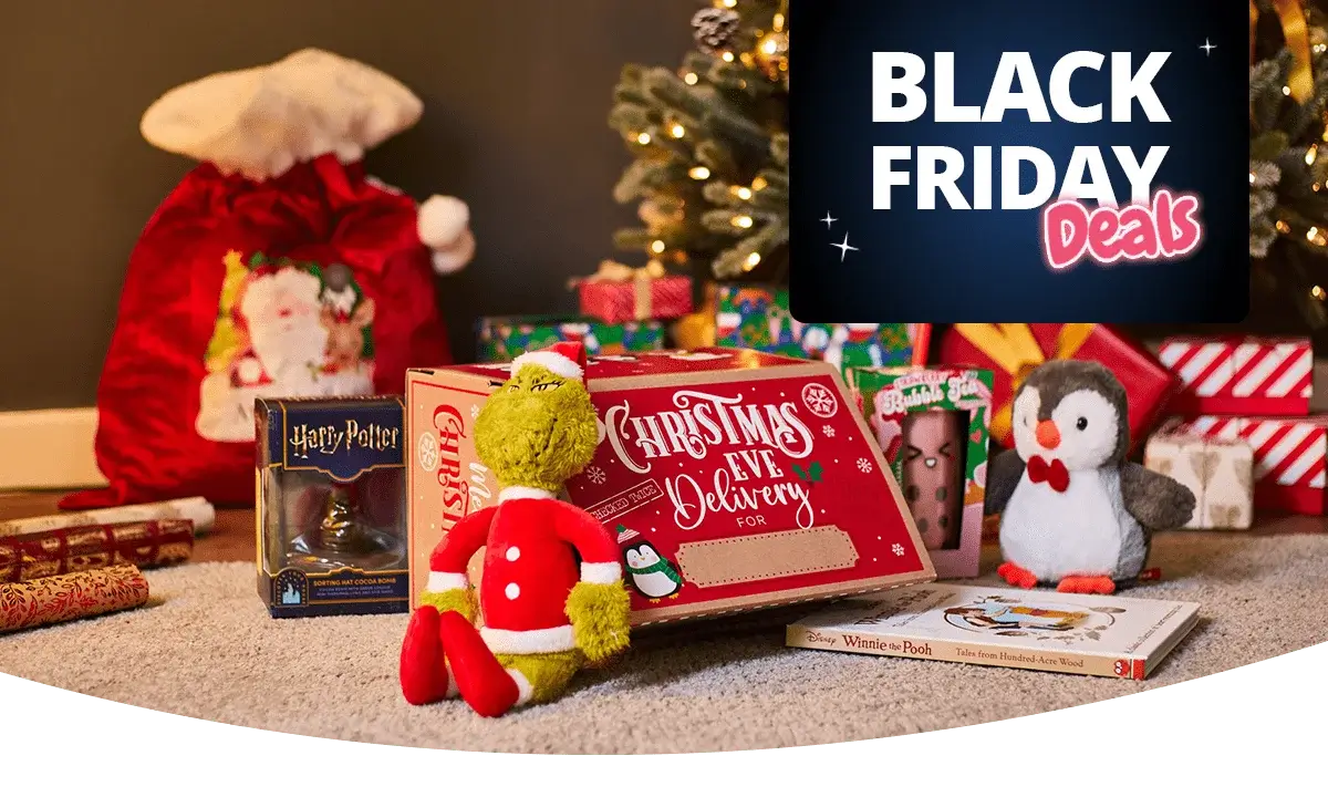 Christmas-themed gift display with toys, books, and festive packaging arranged near a decorated tree, alongside a Black Friday Deals sign.