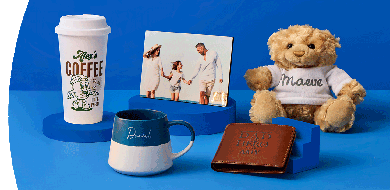 A cosy home display featuring personalised wall art, a wooden clock, a table lamp, framed prints, decorative accessories and a cushion with a highland cow design arranged against a dark blue wall.