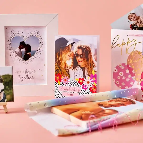A display of personalised photo gifts on a peach background, including a photo frame, greeting cards, a birthday gift bag, a photo mug, and wrapped photo prints. A display of personalised photo gifts on a peach background, including a photo frame, greeting cards, a birthday gift bag, a photo mug, and wrapped photo prints.