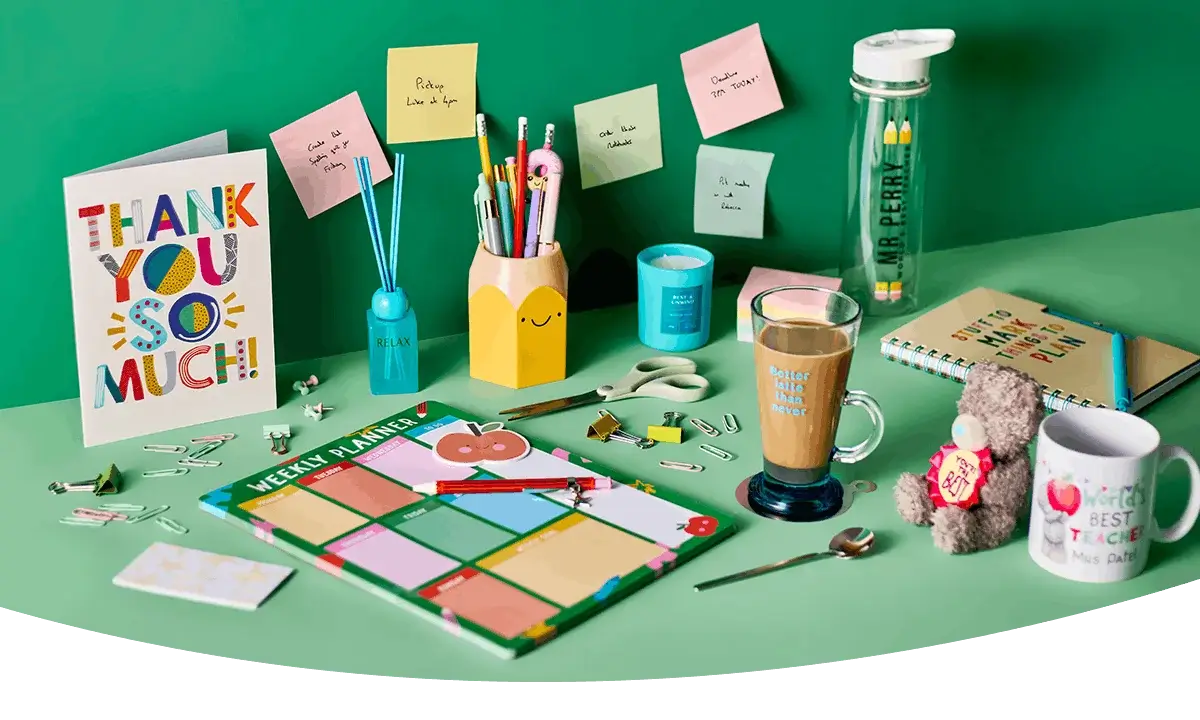 Teacher appreciation setup with thank you card, planner, stationery, mug, water bottle, and small gifts arranged on a green background