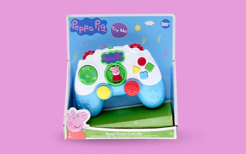 A boxed Peppa Pig electronic games controller designed for young children, featuring large colourful buttons and Peppa Pig graphics, displayed against a pink background.