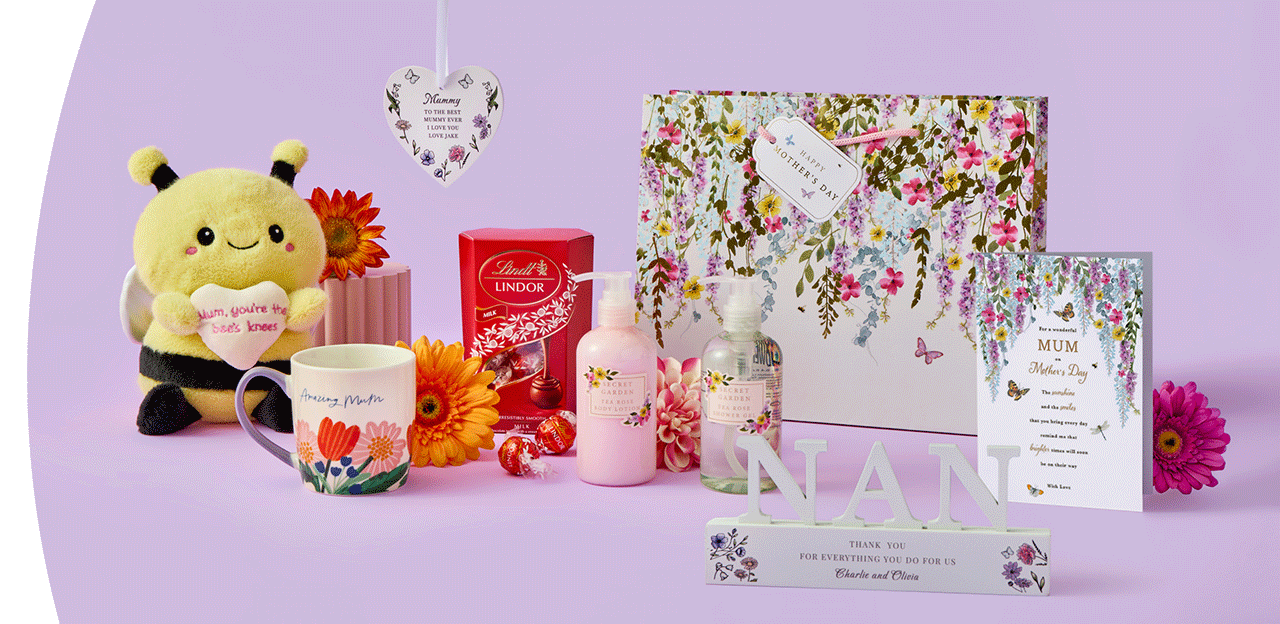 Floral‑themed Mother’s Day gift set featuring a plush bee holding a heart, a flower mug, chocolates, lotion, a decorative heart plaque, a patterned gift box, a framed card, and a NAN ornament arranged on a pastel purple background.