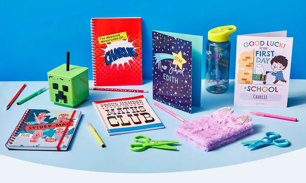 Assorted school supplies and personalised items on a blue surface, including notebooks, pencils, a Minecraft pencil holder, and greeting cards for Edith and Charlie.