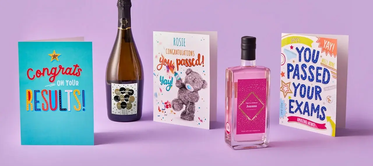 Celebratory display on a purple background with greeting cards, a champagne bottle, and a pink gin bottle congratulating exam success.