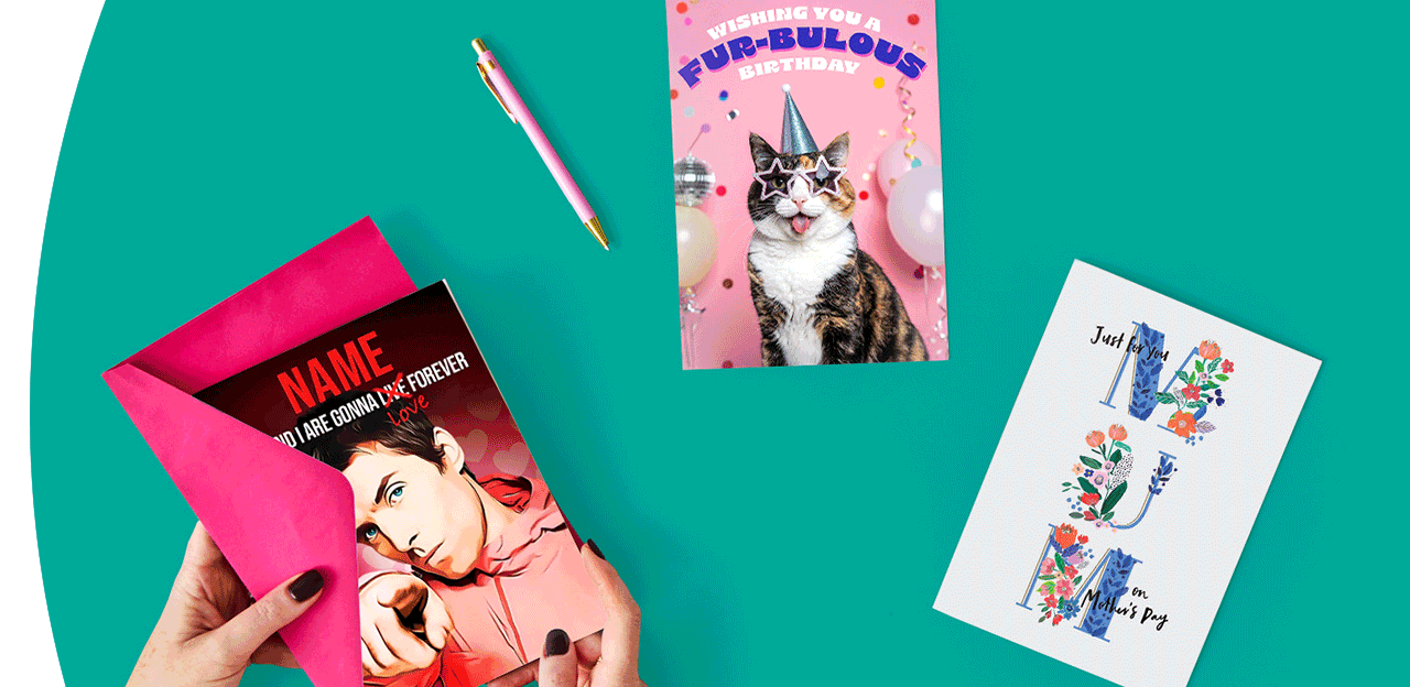 A set of colourful greeting cards arranged on a teal background, including one being placed into a bright pink envelope, a cat‑themed birthday card, and a floral card beside a matching pen.