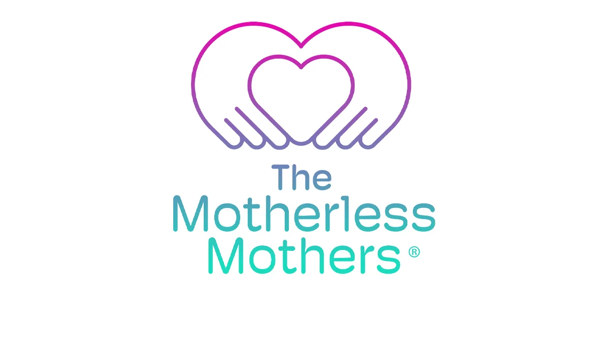 Logo for The Motherless Mothers, showing two stylised hands forming a heart shape in a pink‑to‑purple gradient, with the organisation name centred below in blue and teal text.
