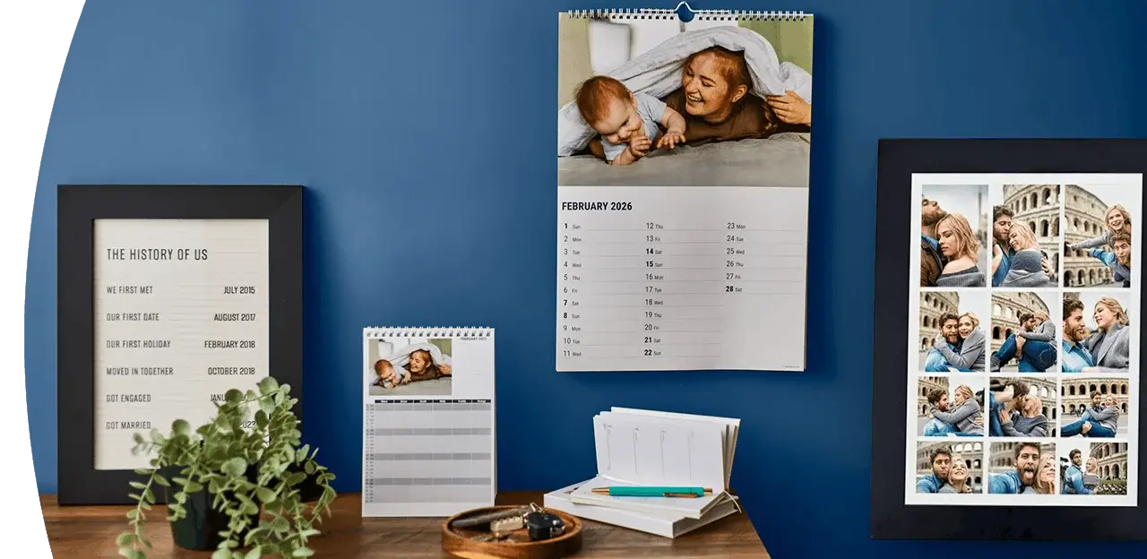 Personalised photo calendars and framed photo prints displayed on a wooden shelf against a blue wall, featuring family and travel photographs. Personalised photo calendars and framed photo prints displayed on a wooden shelf against a blue wall, featuring family and travel photographs.