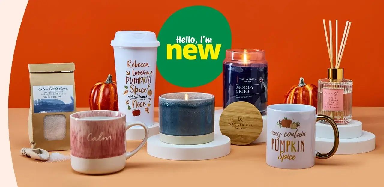 Autumn-themed product display on an orange background, featuring mugs, a candle, bath salts, and a reed diffuser, with a green 'Hello, I'm new' label